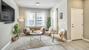 A modern living room with a sofa, chairs, a coffee table, and a TV. - 3BD Modern Home Close to Usafa (Monument)