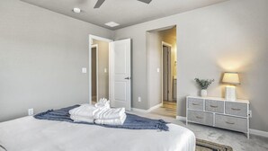 A bedroom with a bed, a ceiling fan, a nightstand with a lamp, and a dresser. - 3BD Modern Home Close to Usafa (Monument)