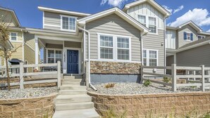A two-story house with a stone foundation, a front porch with steps, and a mailbox. - 3BD Modern Home Close to Usafa (Monument)
