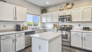 A modern kitchen with white cabinetry, stainless steel appliances, and a large window providing a view of the outdoors. - 3bdquiet Suburbsthe Perfect Get Away (Colorado Springs)