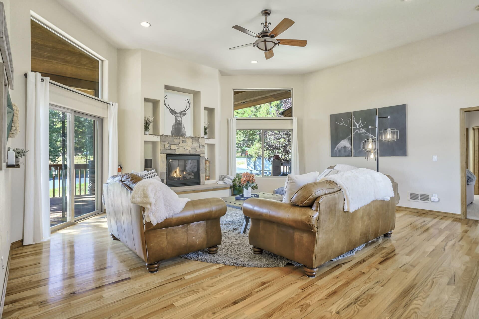 A spacious living room with a fireplace, leather sofas, and a large window overlooking a deck.