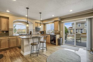 Una cocina amplia con armarios de madera, una isla central con taburetes y vistas al exterior.