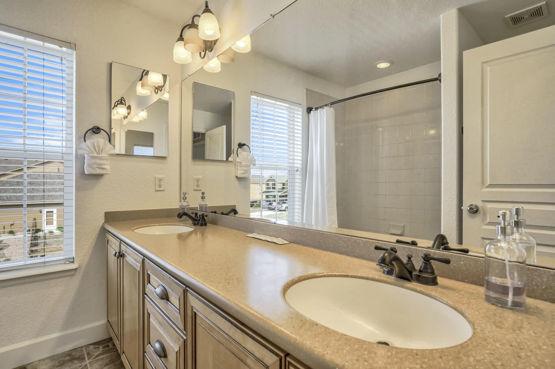 A bathroom with two sinks, a large mirror, and a shower.