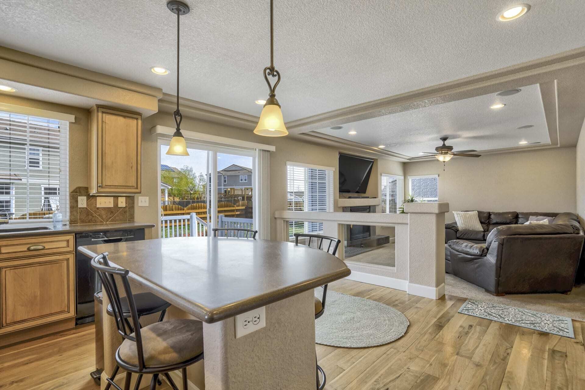 Una cocina moderna con una isla central, comedor con sillas, chimenea y sala de estar con sofá y televisor.