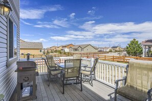 Eine Holzterrasse mit Gartenmöbeln, einem Grill und Blick auf eine Wohngegend mit Häusern und einem Gazebo.
