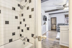 Een moderne badkamer met witte tegels, een badkuip en een douchekop.