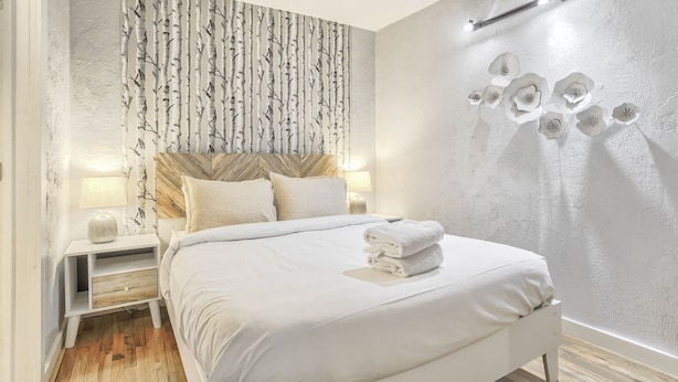 A bedroom with a bed, nightstands, a headboard, and a wall with a tree pattern and flower design. - 2BD Cozy Retreatclose to Red Rocksdogs Welcome! (Colorado Springs)