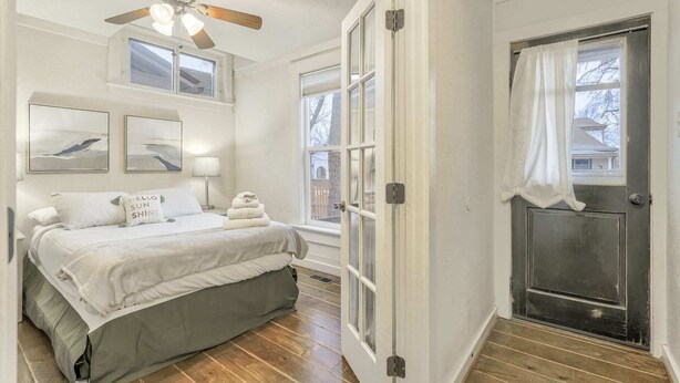 Ein Schlafzimmer mit einem Bett, einem Deckenventilator, zwei Wandleuchten und einem Fenster mit Vorhängen.