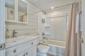 Un baño con lavamanos blanco, espejo, inodoro y bañera.
