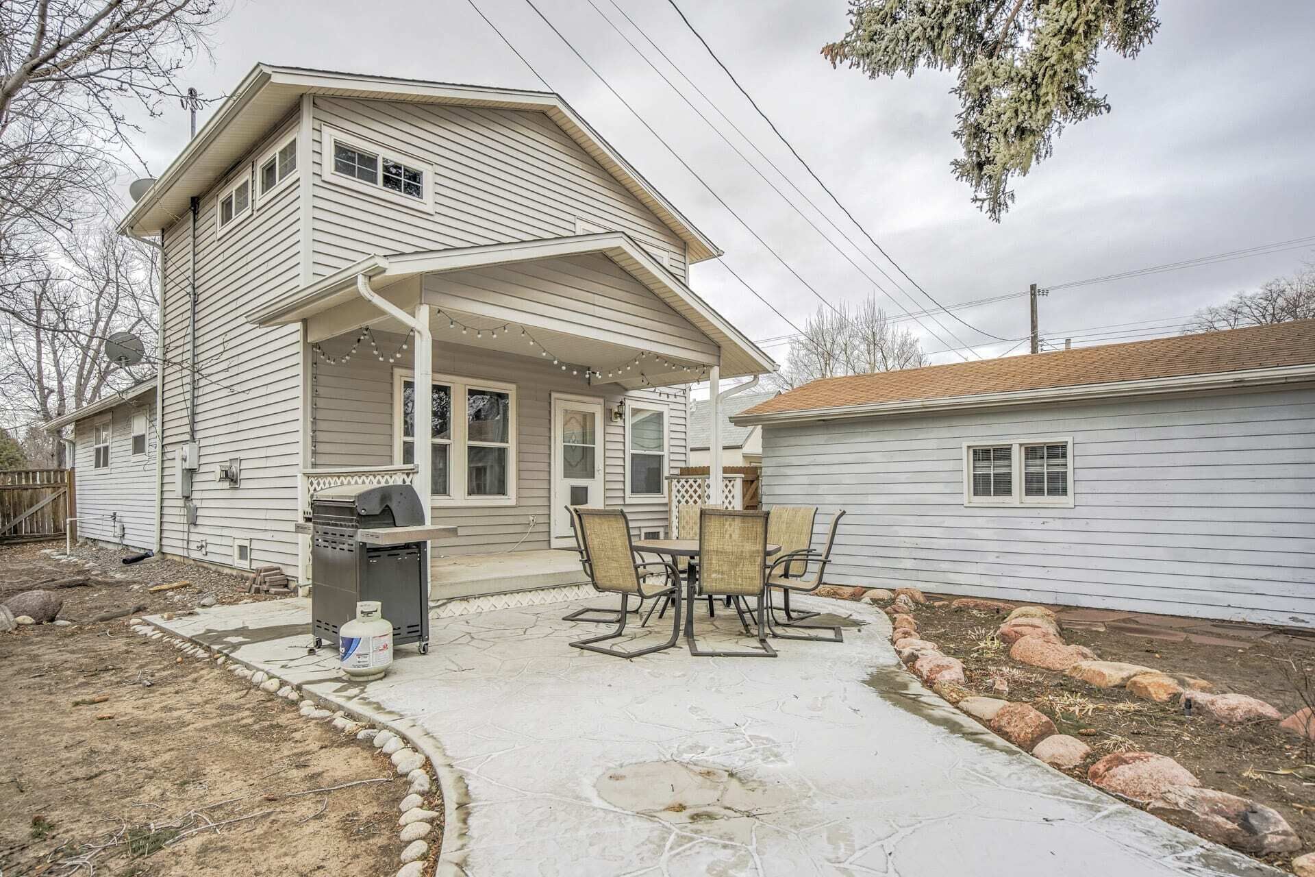 Ein zweistöckiges Haus mit überdachter Terrasse und Grill.