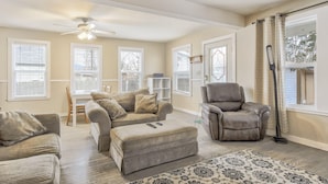 A spacious living room with a beige sofa set, a leather recliner, and a patterned rug.