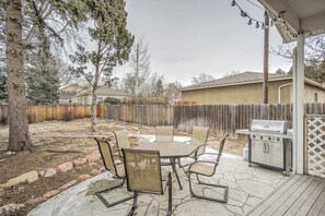 An outdoor patio with a table and chairs, a grill, and a wooden fence. - 2BR Central Location Big Backyard & Dog Friendly! (Colorado Springs)