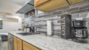 Uma cozinha com bancada de granito, pia, cafeteira e um dispensador de toalhas.