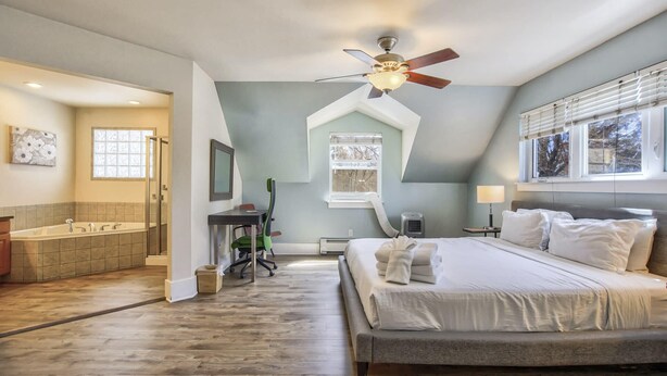 A bedroom with a bed, a ceiling fan, a window with blinds, and a view of the outdoors.