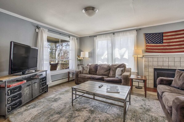 A living room with a television, sofa, coffee table, and a fireplace with an American flag.