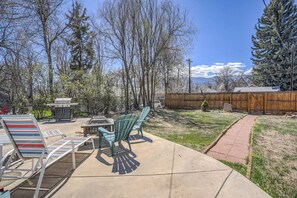 A backyard with a grill, outdoor chairs, and a walking path.