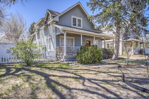 A two-story house with a front porch, a small front yard, and a visible garage.