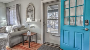 A cozy living room with a sofa, a small table with a lamp, and a blue door with a window. - 1bdlovely Cottagedogs Welcome!near Olympic Training Center (Colorado Springs)