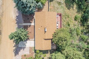 An aerial view of a house with a flat roof, surrounded by trees and a dirt road. - 4BD Palmer Lake Mountain Getaway & Local Attractions (Palmer Lake)