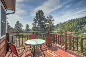 A wooden deck with a table and chairs, overlooking a forested area. - 4BD Palmer Lake Mountain Getaway & Local Attractions (Palmer Lake)