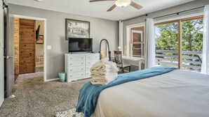 Une chambre avec un lit, une télévision, un bureau et un balcon.