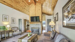 Un salon chaleureux avec une cheminée, un plafond en bois et des sièges confortables.