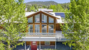 Une cabane en bois dotée de grandes fenêtres, d’une porte rouge et d’un porche abrité.