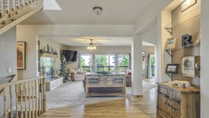 A spacious living area with a wooden floor, a central seating area with a sofa and a coffee table, and a staircase with a wooden railing.