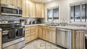A modern kitchen with wooden cabinets, stainless steel appliances, a double sink, and a window providing natural light. - 5BR 💖heart Of Old Colorado Cityfoosball 💖 (Colorado Springs)