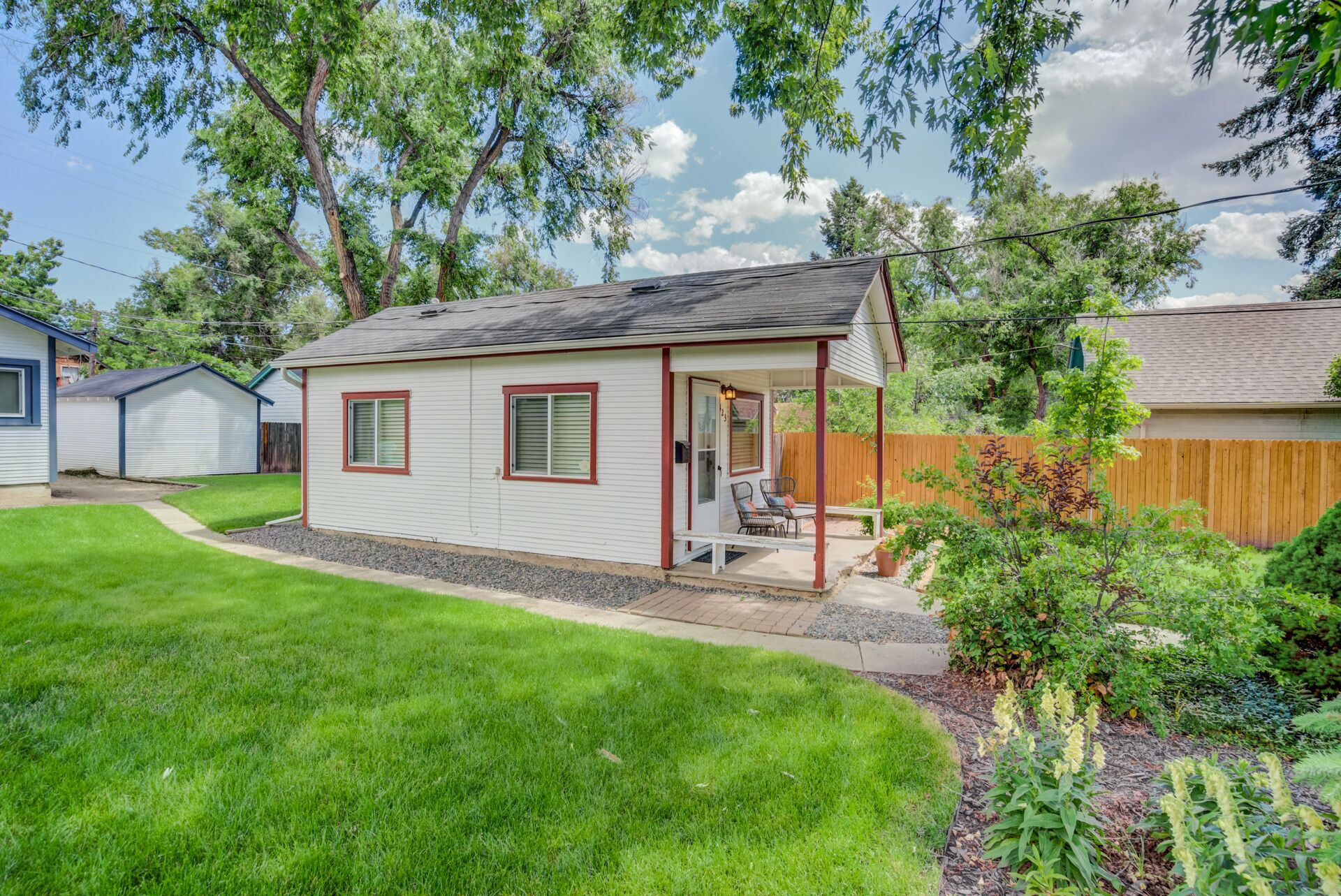 A single-story house with a covered porch, a small garden, and a wooden fence.