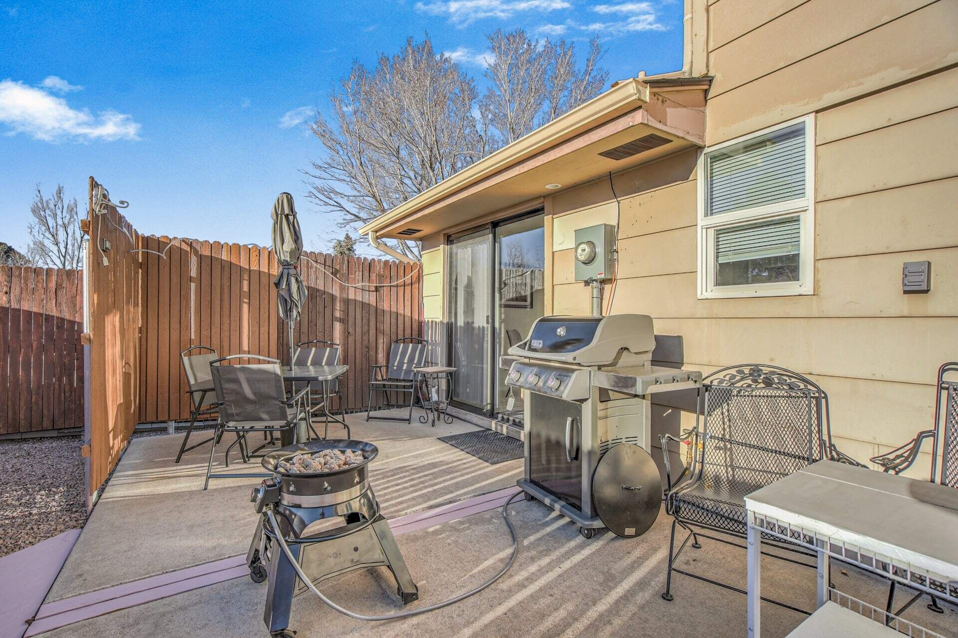 A backyard with a barbecue grill, outdoor seating, and a wooden fence.