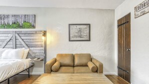 Ett rum med ett träbord, en soffa, en säng, en karta på väggen och en dörr med en skylt.