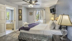 A bedroom with a bed, a ceiling fan, a TV, a bedside lamp, and a window with curtains. - 6bdfamily Mountain Getawayhot Tubminutes to Pikes Peak and Charis College (Woodland Park)