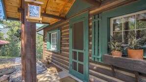 A log cabin with a wooden porch, a green door, and a window with shutters. - Wine Gazebopikes Peak Mountain Log Cabin for 2 (Cascade)