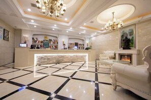 A hotel lobby with a reception desk, a fireplace, and a chandelier. - Xi Er Dun Hotel (Shuyang)