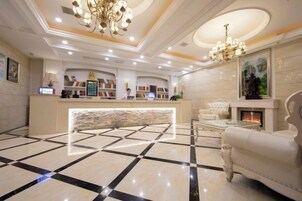 Un vestíbulo de hotel con mostrador de recepción, chimenea y candelabro.