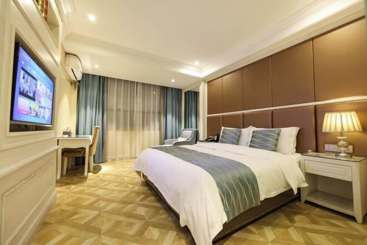 A hotel room with a bed, a desk, a television, and a nightstand.