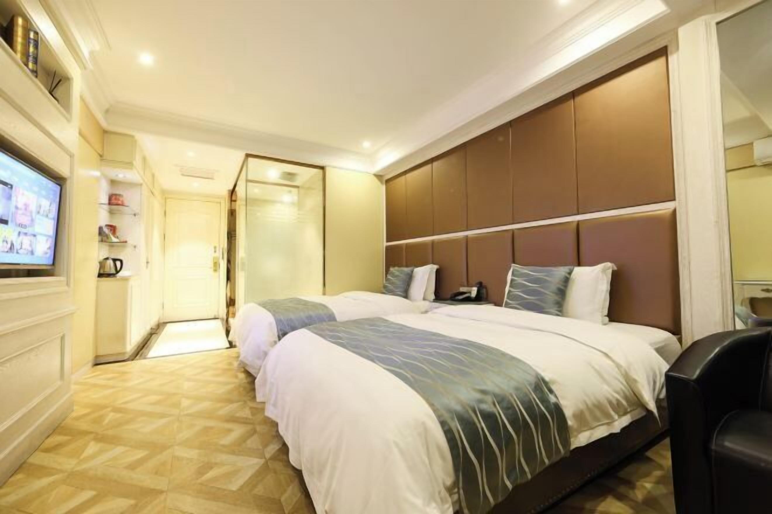 Quarto de hotel com duas camas, televisão e minibar.