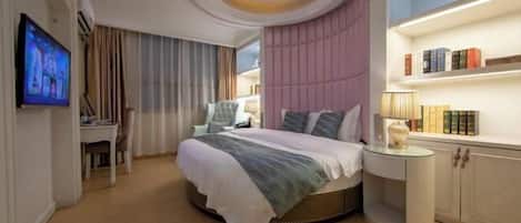 Un dormitorio moderno con una cama redonda, un televisor, un escritorio y una estantería.
