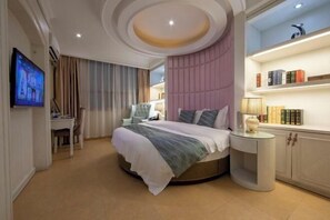 A modern bedroom with a round bed, a TV, a desk, and a bookshelf. - Xi Er Dun Hotel (Shuyang)
