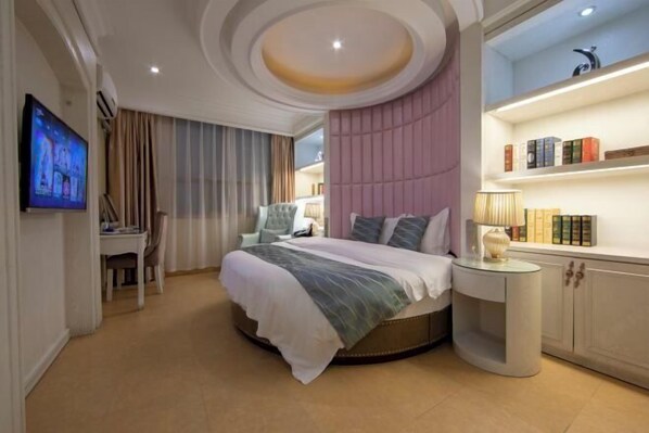 A modern bedroom with a round bed, a TV, a desk, and a bookshelf. - Xi Er Dun Hotel (Shuyang)