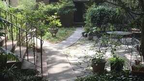 Un sendero de ladrillos que conduce a una casa con un porche cubierto y plantas en macetas.