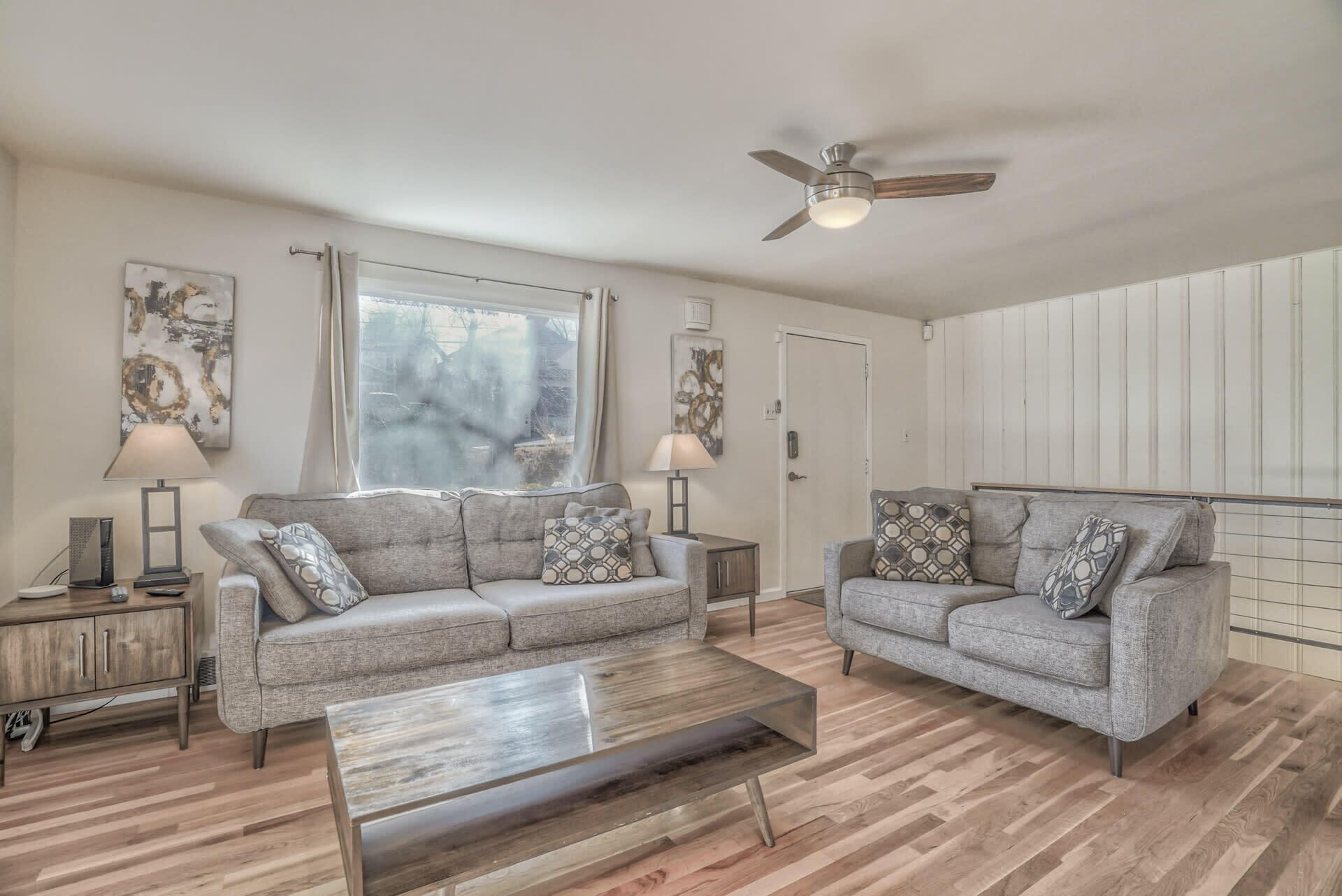 A living room with two grey sofas, a wooden coffee table, and a ceiling fan.