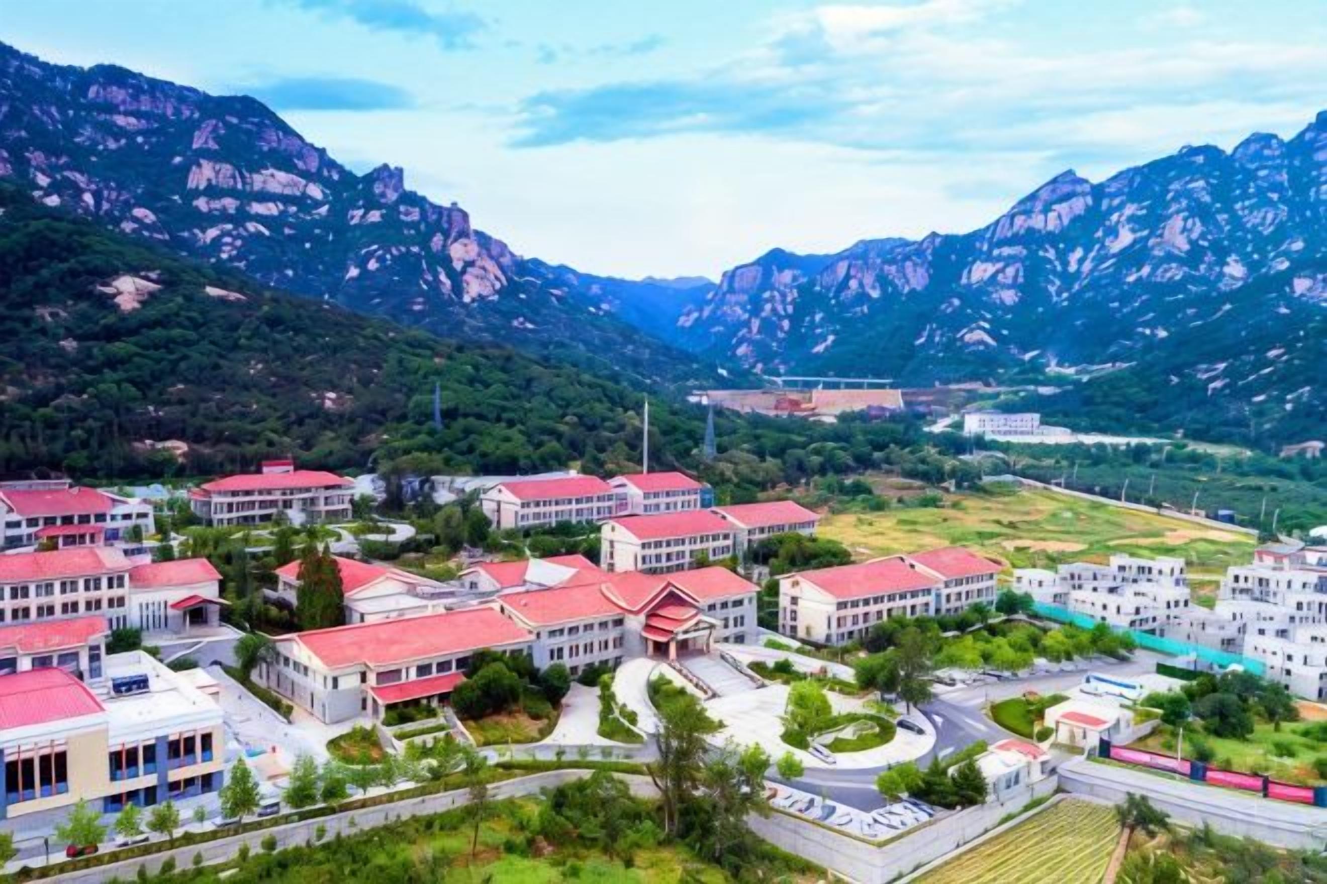 A residential area with multiple buildings, roads, and a mountainous backdrop.