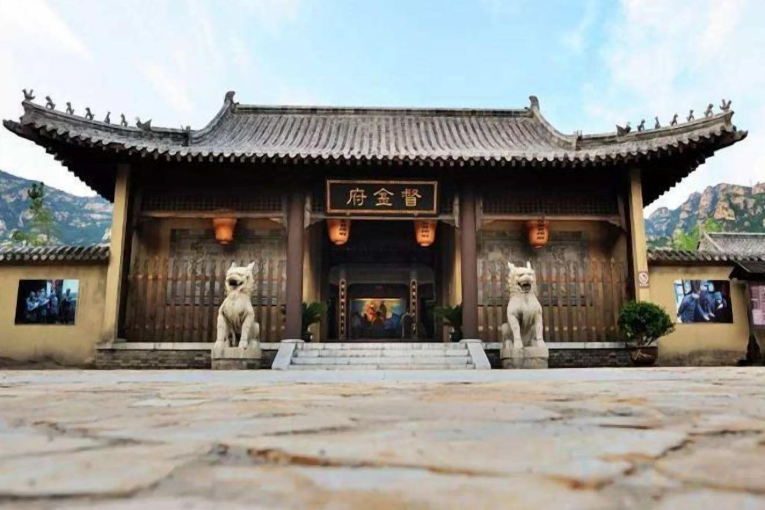 A traditional Chinese building with a tiled roof, a signboard, and two stone lion statues at the entrance.