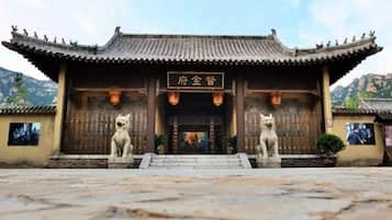 A traditional Chinese building with a tiled roof, a signboard, and two stone lion statues at the entrance.