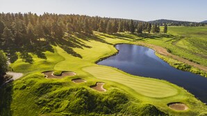 Golfkenttä, jossa on lampi, ja jonka ympärillä on puita ja kukkuloita.