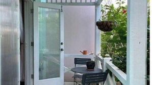A covered patio with a sliding glass door, a small table with chairs, and a potted plant. - Southgate courtyard<br>Unit 20 (Christiansted)
