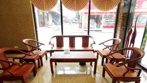 A seating area with wooden furniture and a view of the street through large windows. - Zhongya Hotel (Nanning)