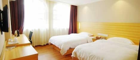 A hotel room with two beds, a desk, and a window with curtains.